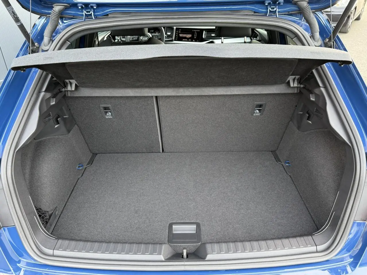 Coffre ouvert vu de l'arrière d'une Audi A1 Sportback 30 TFSI bleu Ascari avec intérieur de coffre gris.