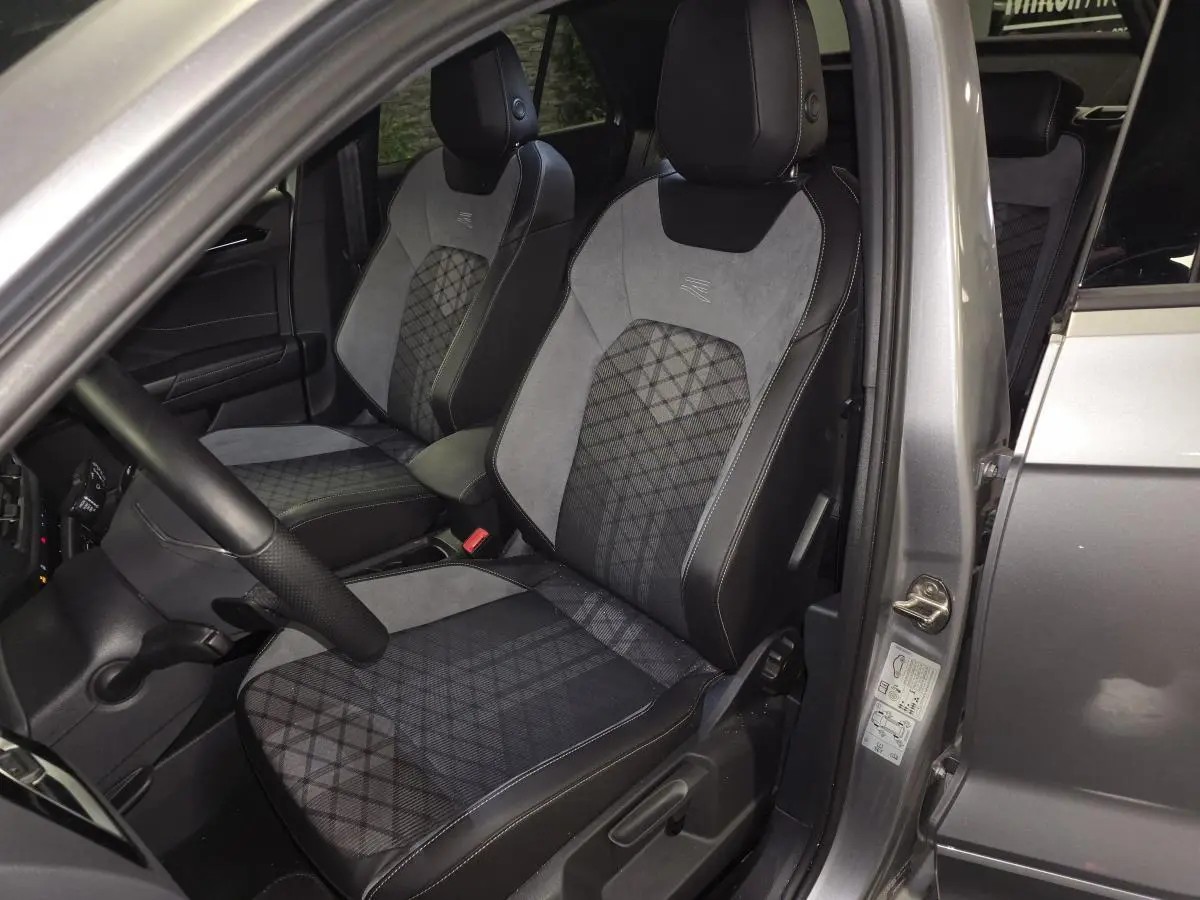 Vue intérieure côté conducteur du Volkswagen T-Roc gris 2025, mettant en valeur les sièges avant R-Line en tissu et similicuir.