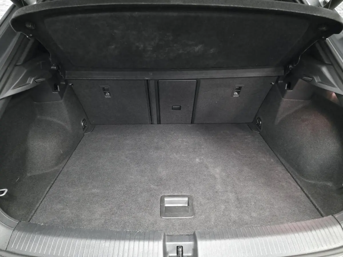 Coffre ouvert vu de l'arrière d'un Volkswagen T-Roc gris, montrant un espace de chargement propre et spacieux.
