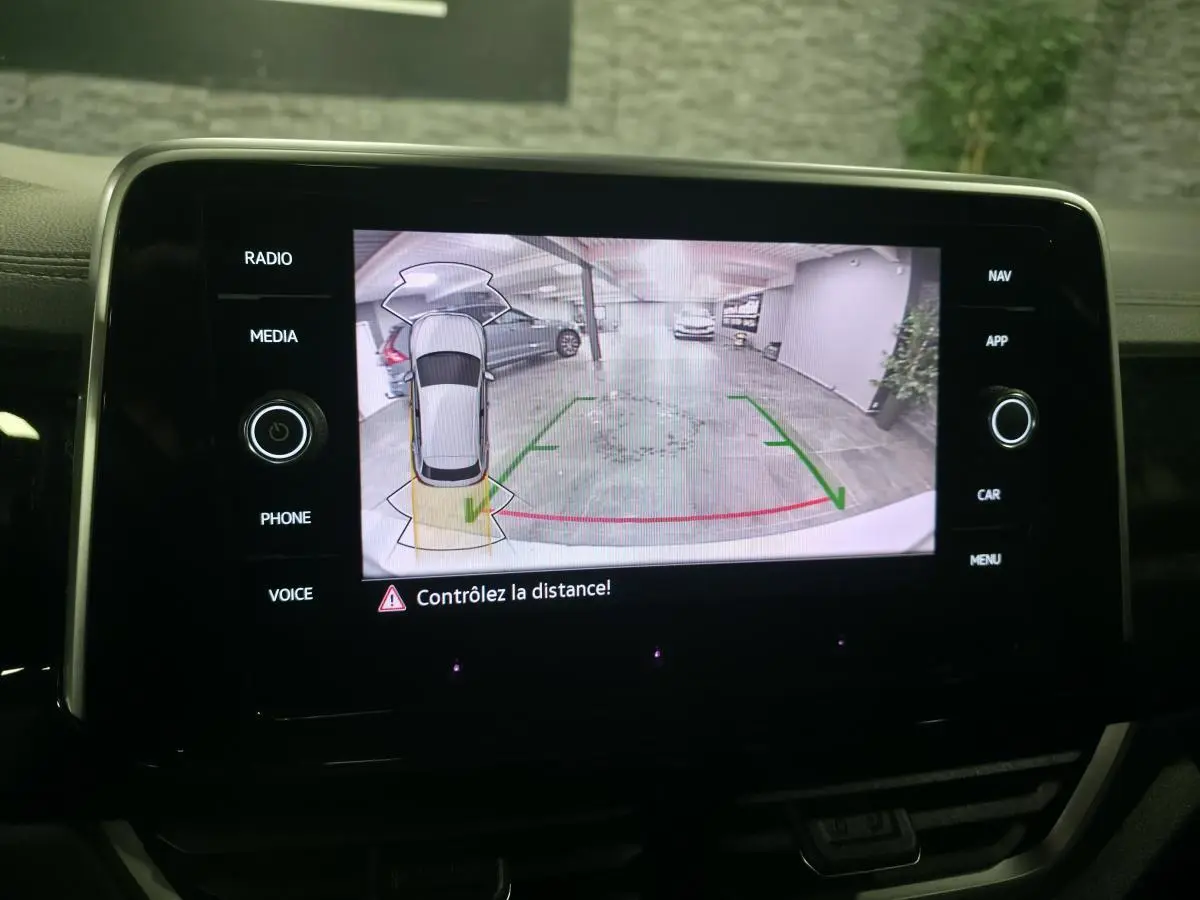 Écran tactile intérieur affichant la caméra de recul du Volkswagen T-Roc gris, vue arrière avec lignes de guidage vertes et rouges.