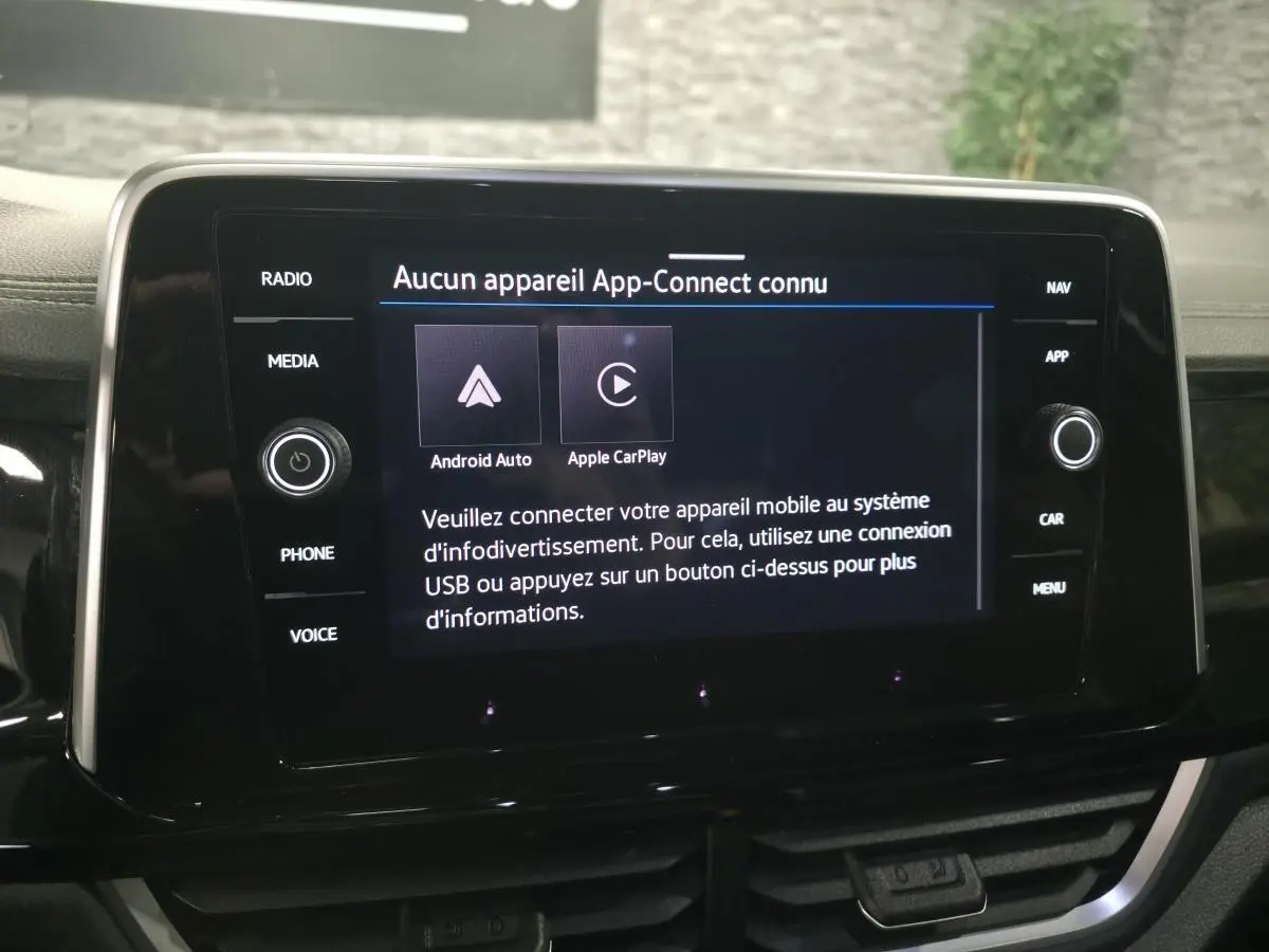 Écran tactile central noir affichant le menu App-Connect dans l'habitacle du Volkswagen T-Roc gris.