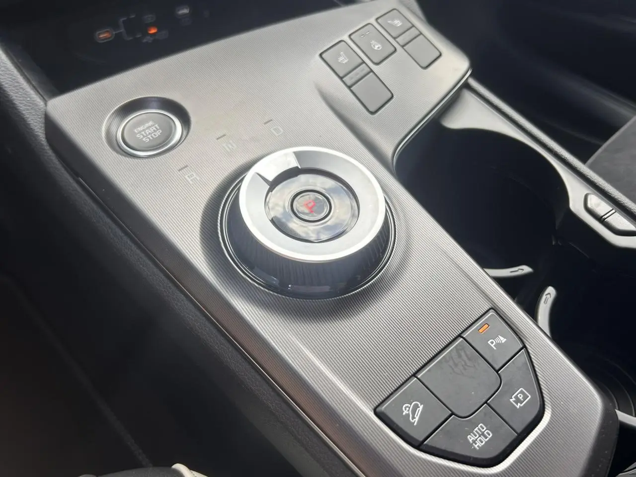 Gros plan sur la console centrale du Kia Sportage noir 2026, avec molette de sélection de vitesse et boutons de contrôle.