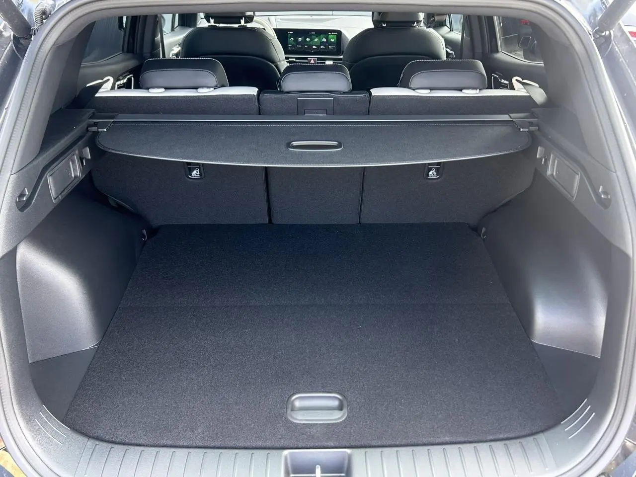 Vue arrière du coffre noir du Kia Sportage 2026 avec cache-bagages et sièges arrière rabattables visibles.