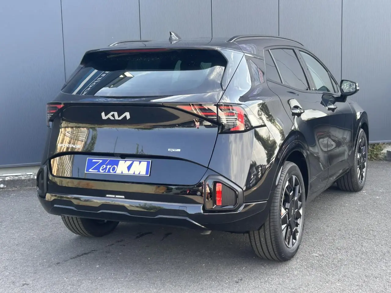 Vue 3/4 arrière droite du KIA SPORTAGE noir métallisé 2026 avec feux arrière LED et jantes alliage 19 pouces.