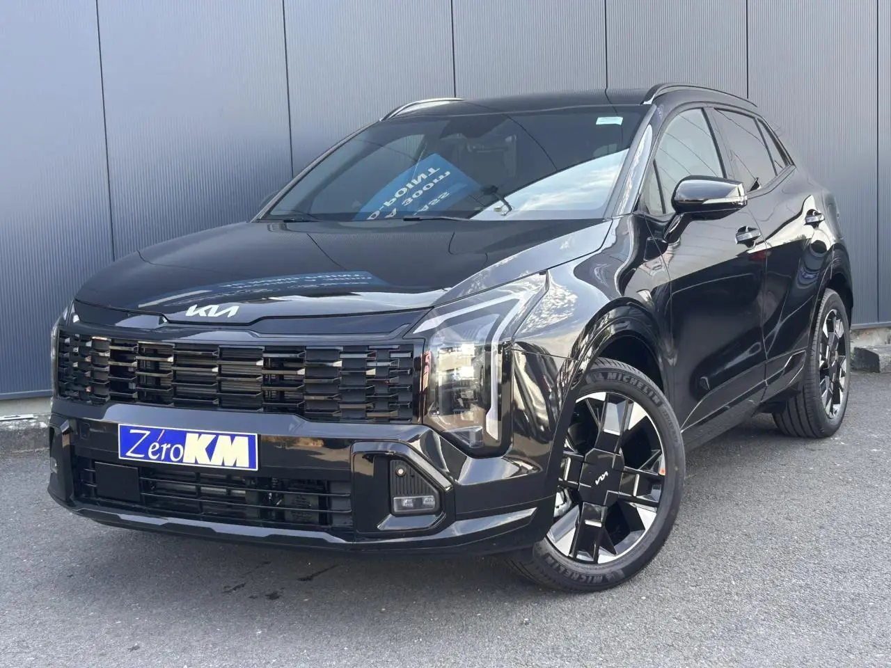 KIA Sportage 2026 noir métallisé en 3/4 avant droit avec jantes alliage 19 pouces et calandre noire distinctive.
