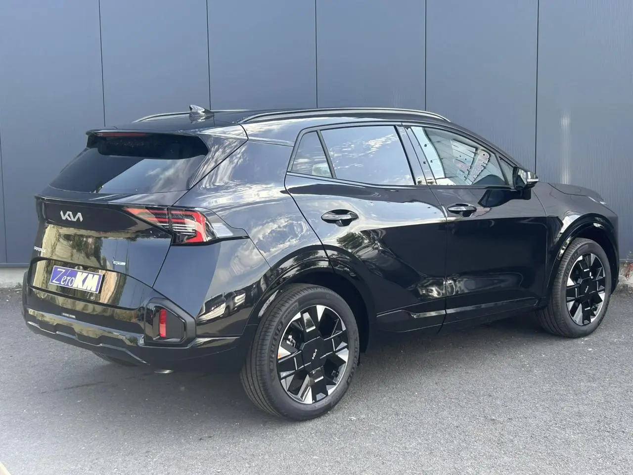 KIA SPORTAGE noir métallisé vue 3/4 arrière droit avec jantes alliage noires et feux arrière LED.