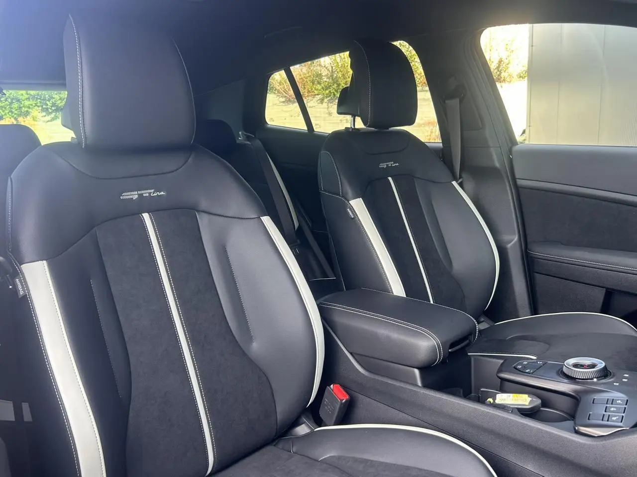 Vue intérieure sur les sièges avant bi-ton noir et gris du KIA Sportage 2026 GT-line avec accoudoir central.