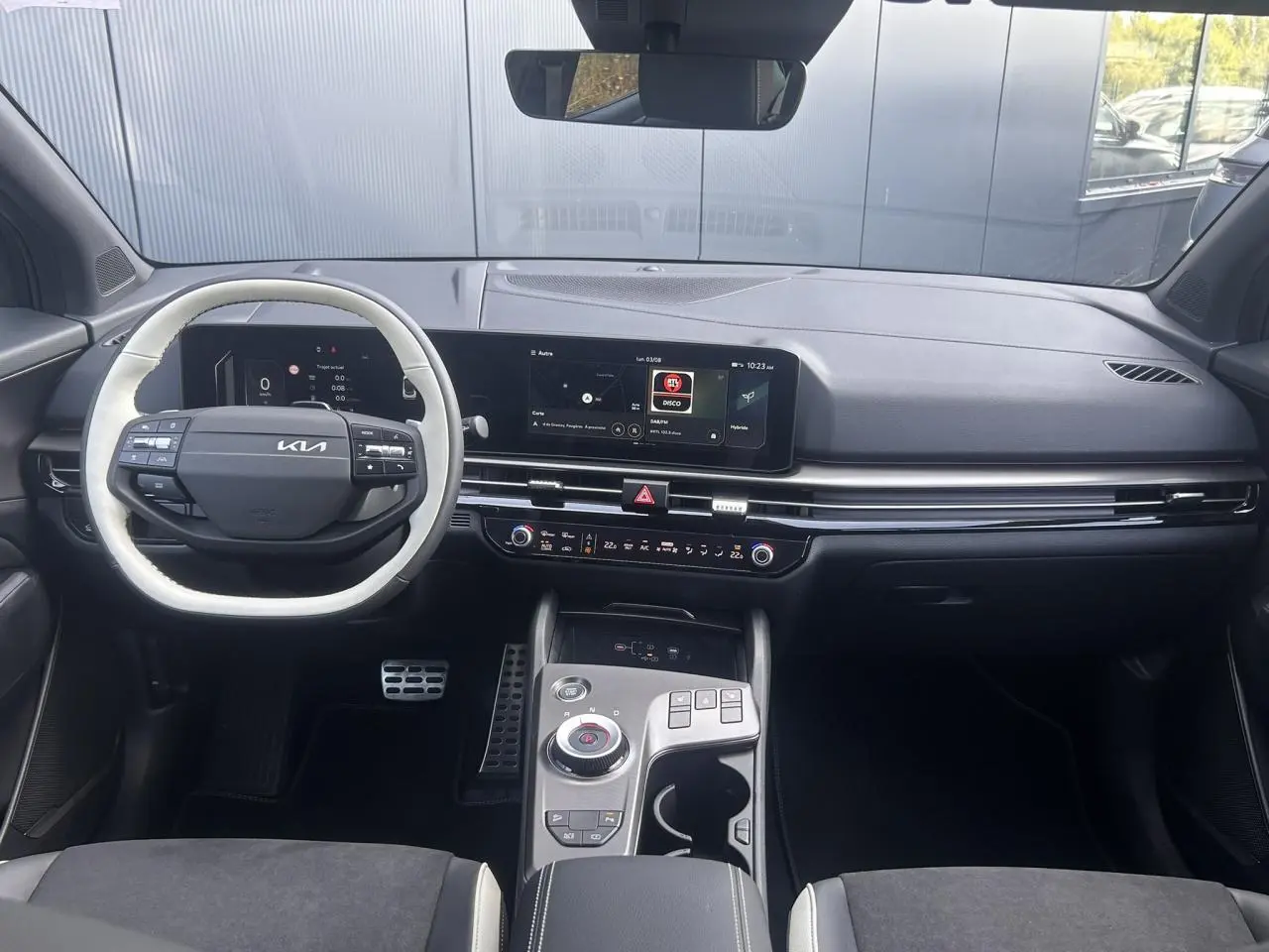 Vue intérieure avant du tableau de bord noir du Kia Sportage 2026 avec écran tactile large et volant bi-ton.