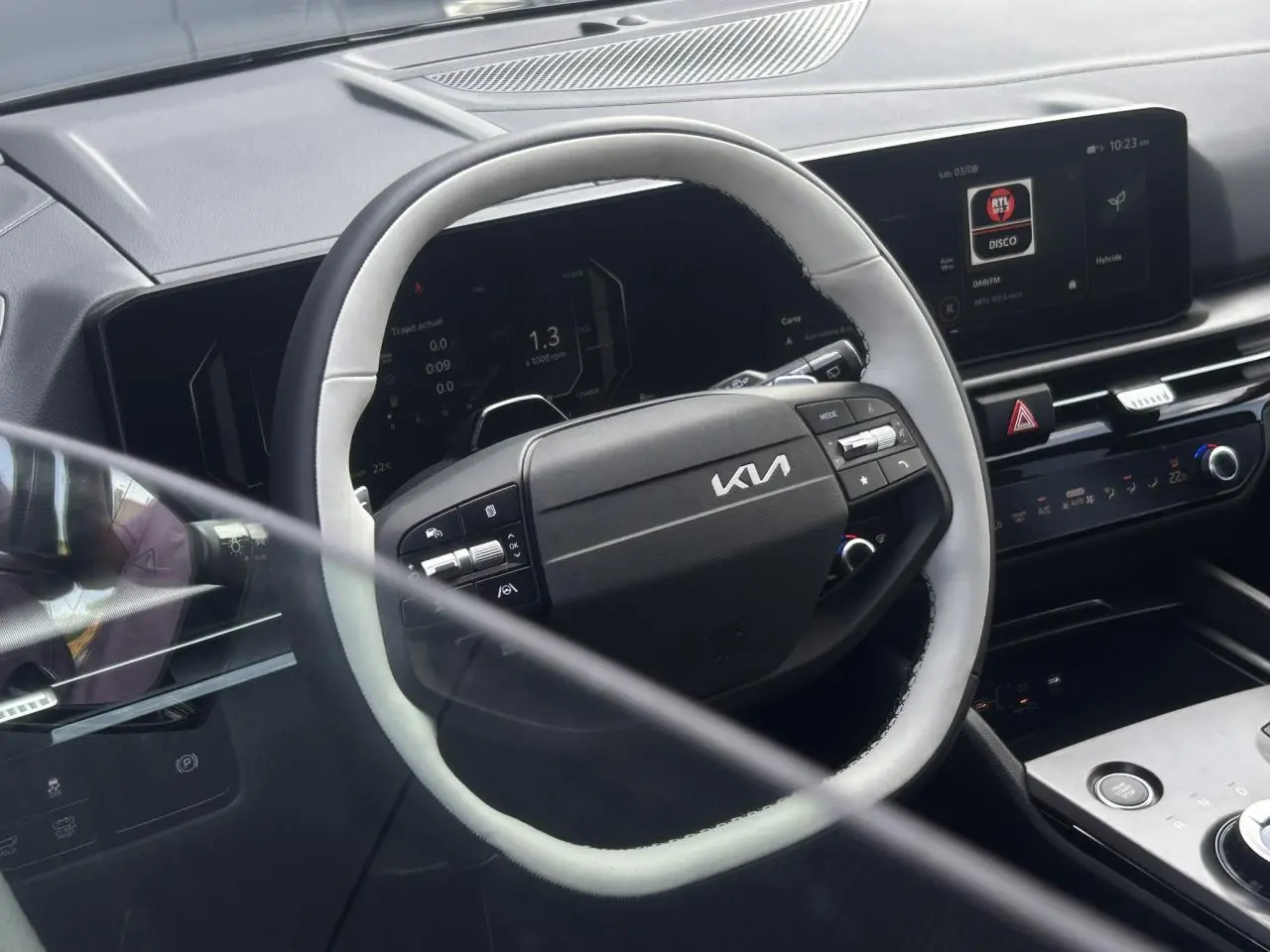 Vue intérieure du volant bi-ton noir et gris du Kia Sportage 2026 avec tableau de bord digital et écran tactile.