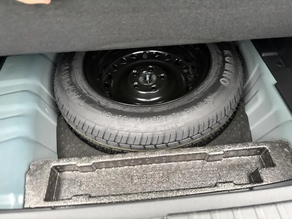 Vue rapprochée de la roue de secours noire dans le coffre du Renault Arkana 2025 Bleu Zanzibar Metal.