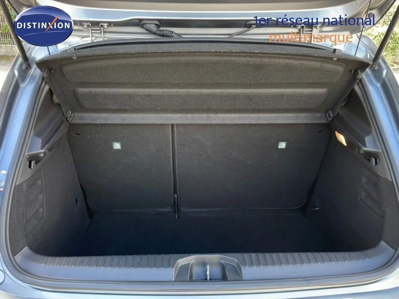 Coffre ouvert vu de l'arrière d'une Renault Clio 2025 gris schiste métal, espace de rangement vide et propre.