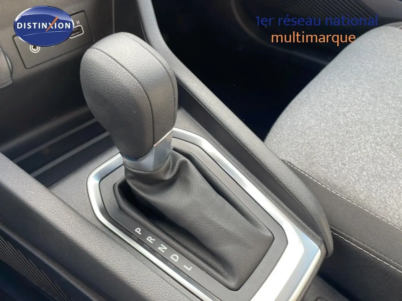 Gros plan sur le levier de vitesse automatique en cuir noir de la Renault Clio 2025, intérieur tissu gris.