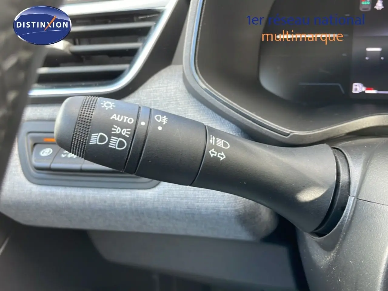 Gros plan sur la commande des feux et clignotants à gauche du volant dans l’habitacle gris de la Renault Clio 2025.