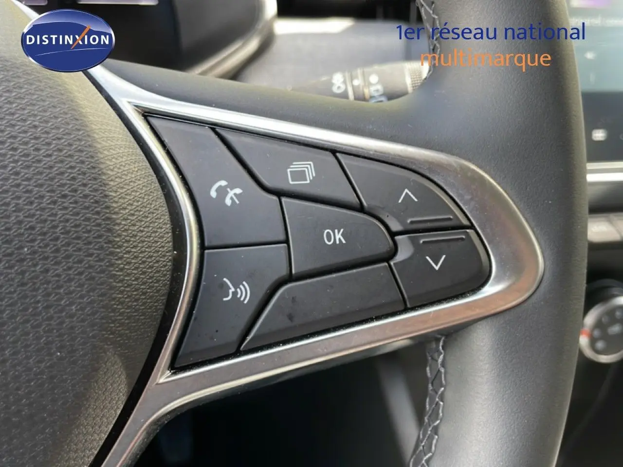 Gros plan sur les commandes multifonctions à droite du volant en cuir noir de la Renault Clio gris schiste 2025.