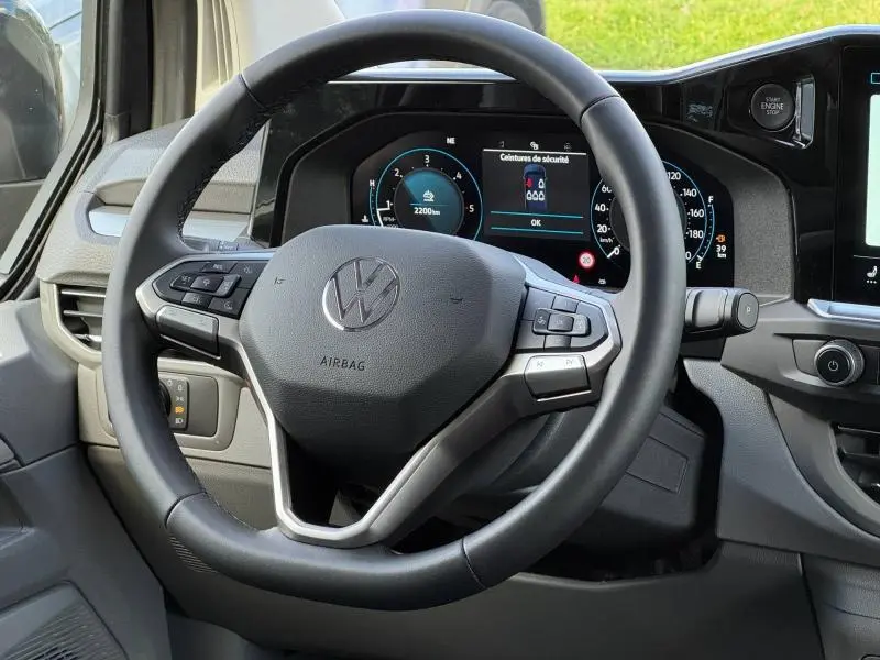 Vue rapprochée du volant cuir multifonction et du tableau de bord numérique du Volkswagen Transporter FGN 2025.