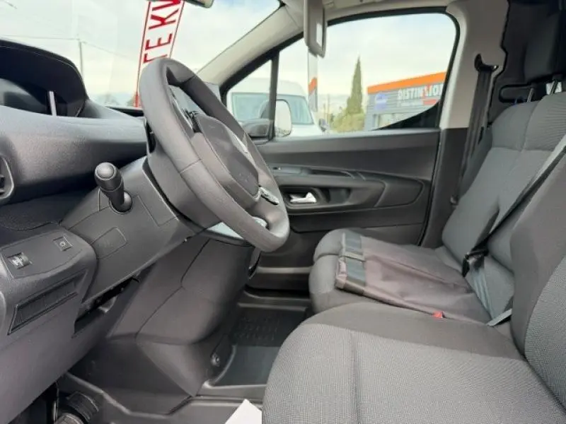 Vue intérieure côté conducteur du Peugeot Partner XL 2025, sièges gris et volant multifonction visible.
