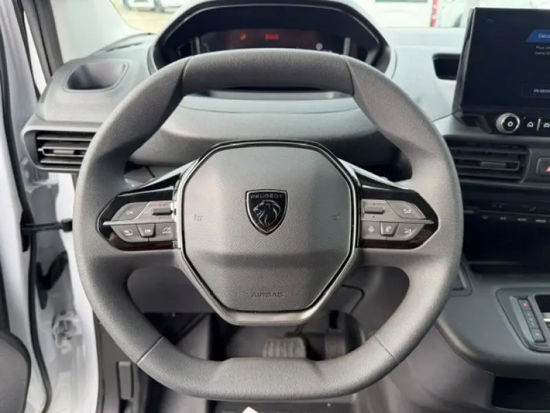 Vue rapprochée du volant multifonction noir du Peugeot Partner XL 2025, avec tableau de bord et écran tactile visibles.