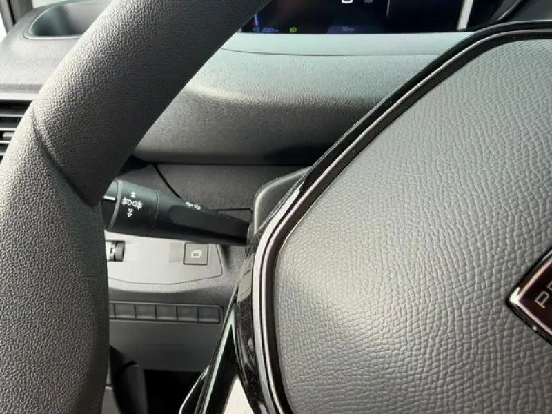 Gros plan sur le volant noir texturé et la commande des feux à gauche dans l'habitacle du Peugeot Partner 2025.