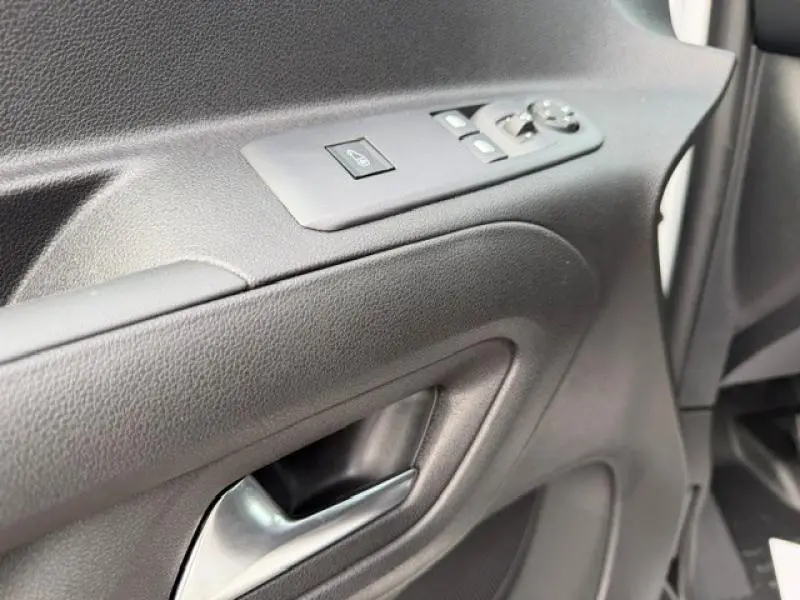 Gros plan sur la porte intérieure côté gauche du Peugeot Partner blanc Icy, montrant poignée et commandes des vitres.