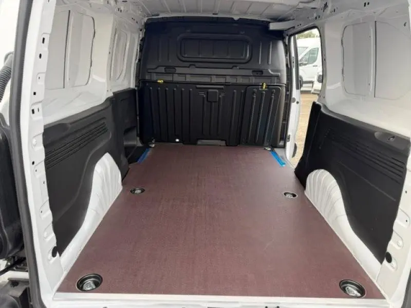 Vue intérieure arrière du Peugeot Partner XL blanc Icy montrant l'espace de chargement avec plancher plat et cloison pleine noire.