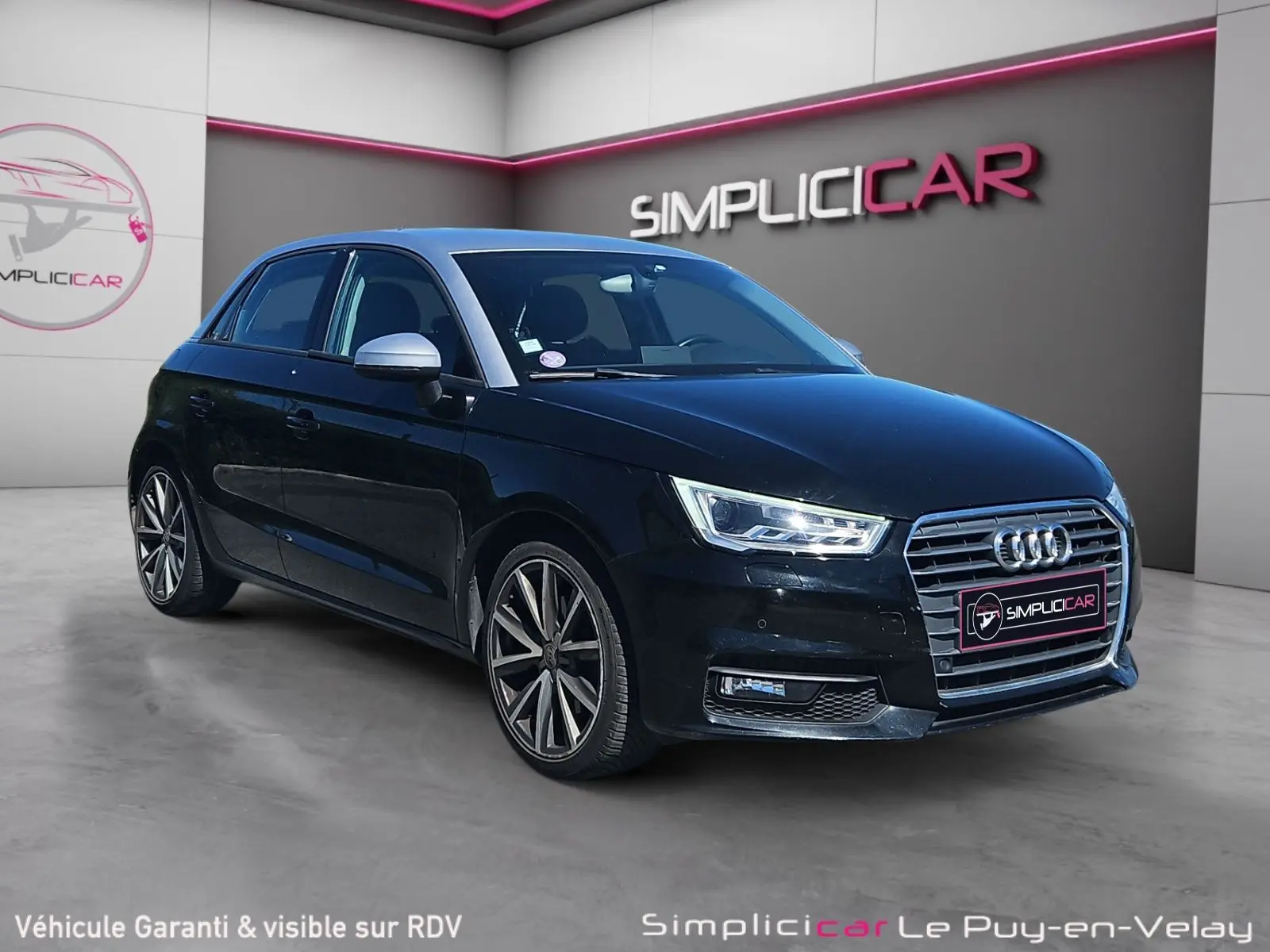 Audi A1 Sportback noir vue 3/4 avant droit, avec jantes alliage 17 pouces et phares LED allumés.