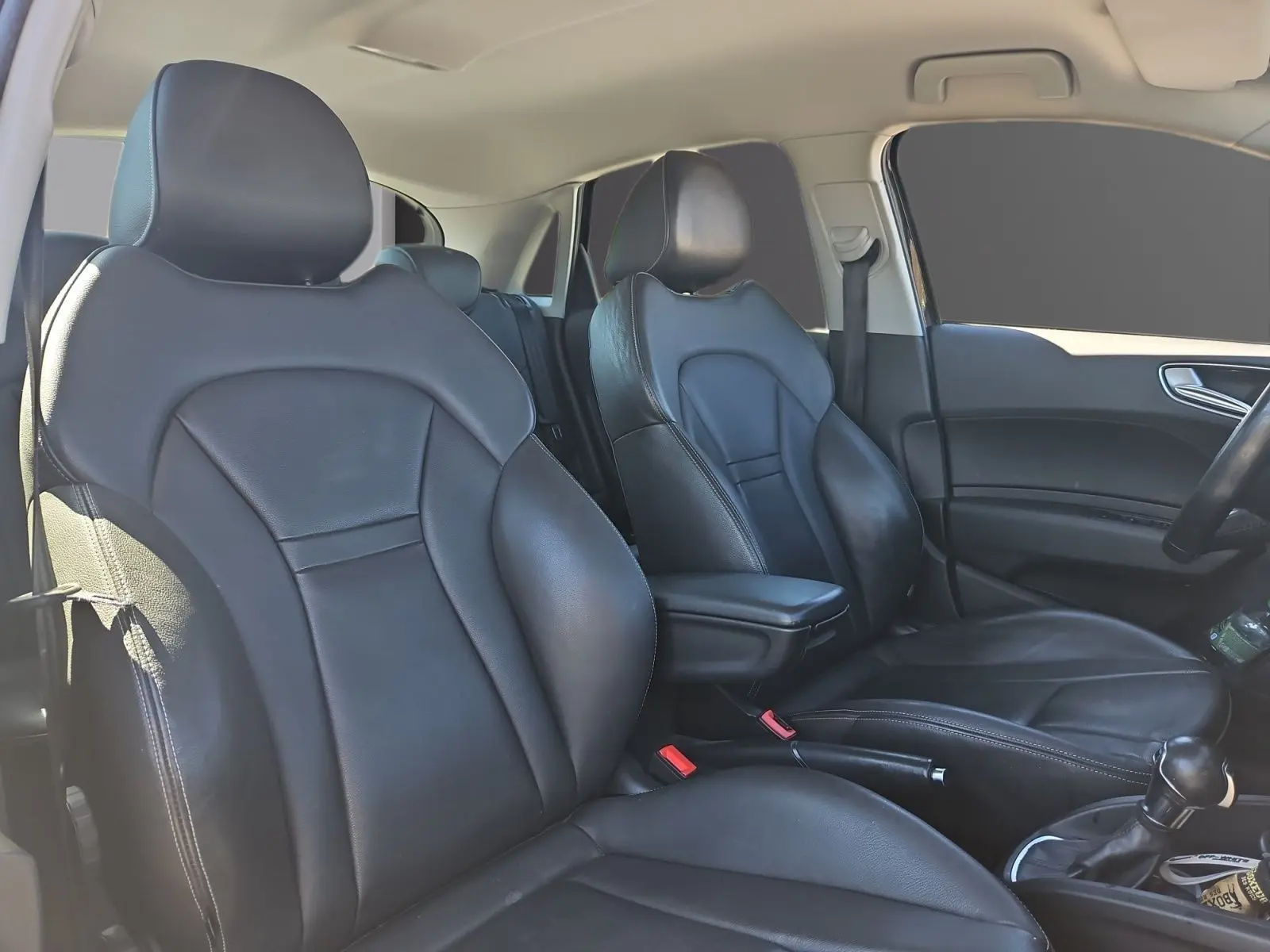 Vue intérieure de l’Audi A1 Sportback 2016 montrant les sièges baquets en cuir noir avec accoudoir central et volant sport.