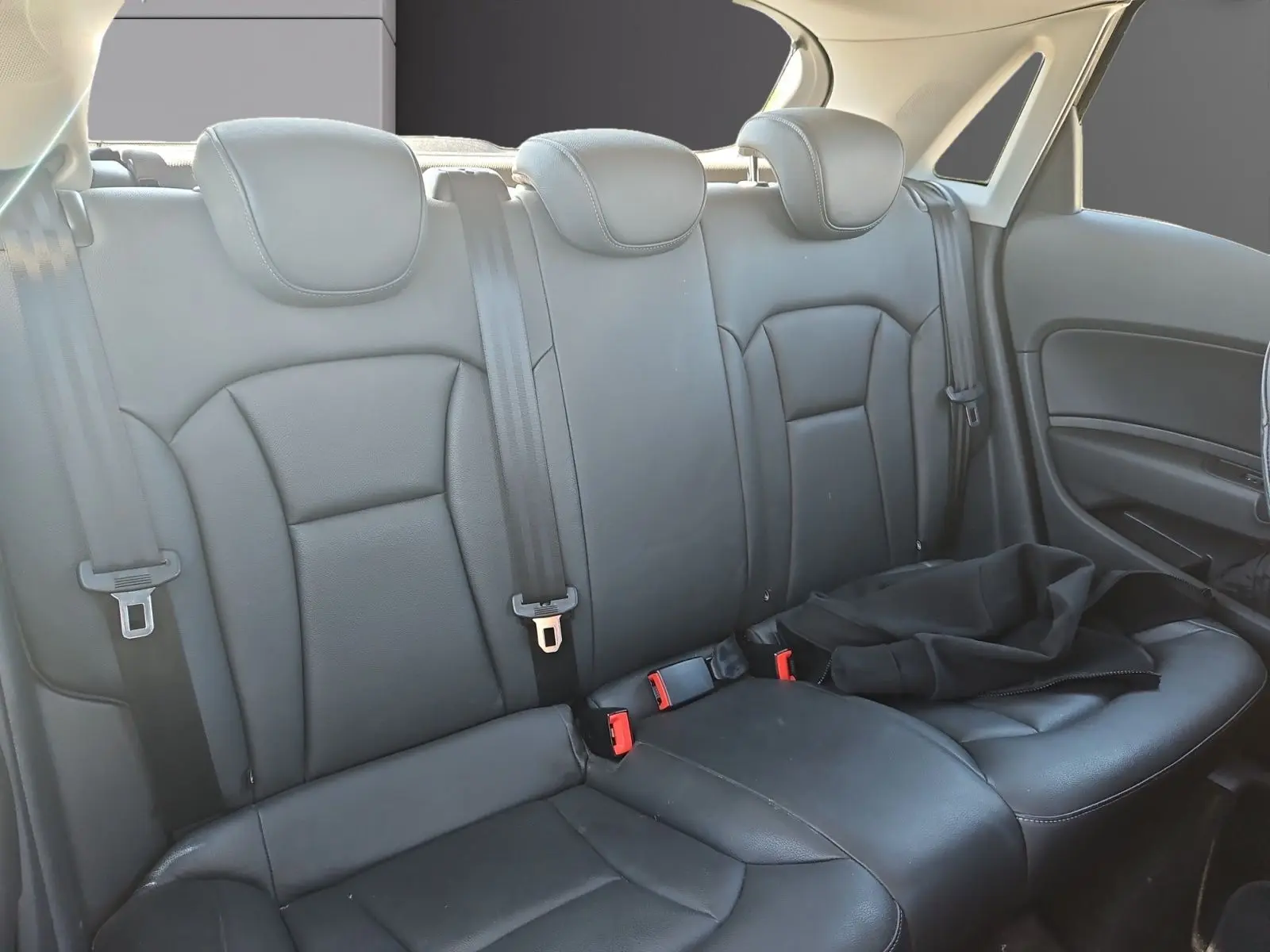 Vue intérieure des sièges arrière en cuir noir de l'Audi A1 Sportback 2016, avec ceinture de sécurité et appuie-têtes.