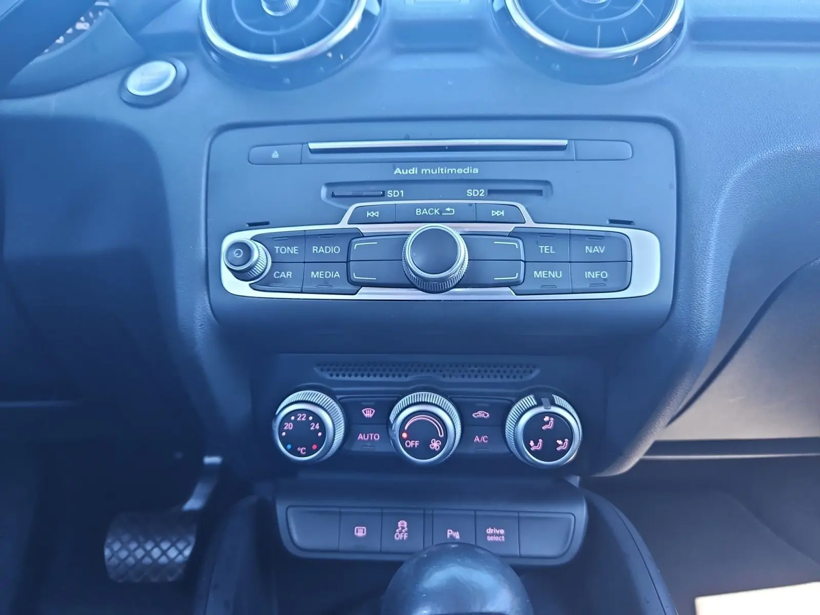 Vue rapprochée du tableau de bord noir de l’Audi A1 Sportback 2016, montrant la console multimédia et les commandes de climatisation.