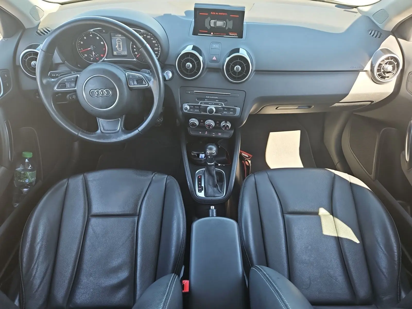 Vue intérieure frontale de l’Audi A1 Sportback 2016 avec sièges baquets cuir noir et console centrale avec boîte auto.