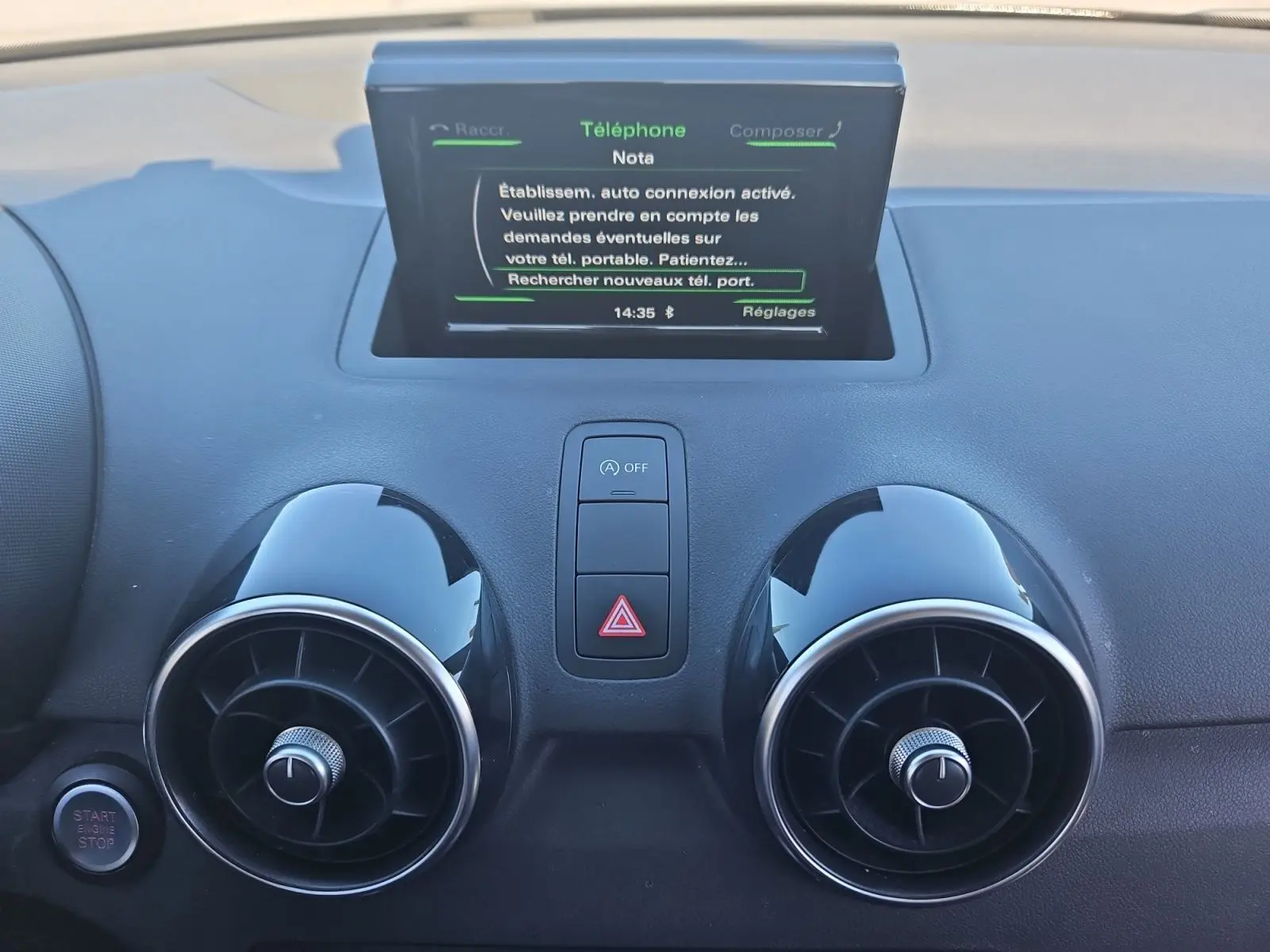 Vue rapprochée du tableau de bord noir de l'Audi A1 Sportback 2016, avec écran tactile et aérateurs ronds chromés.