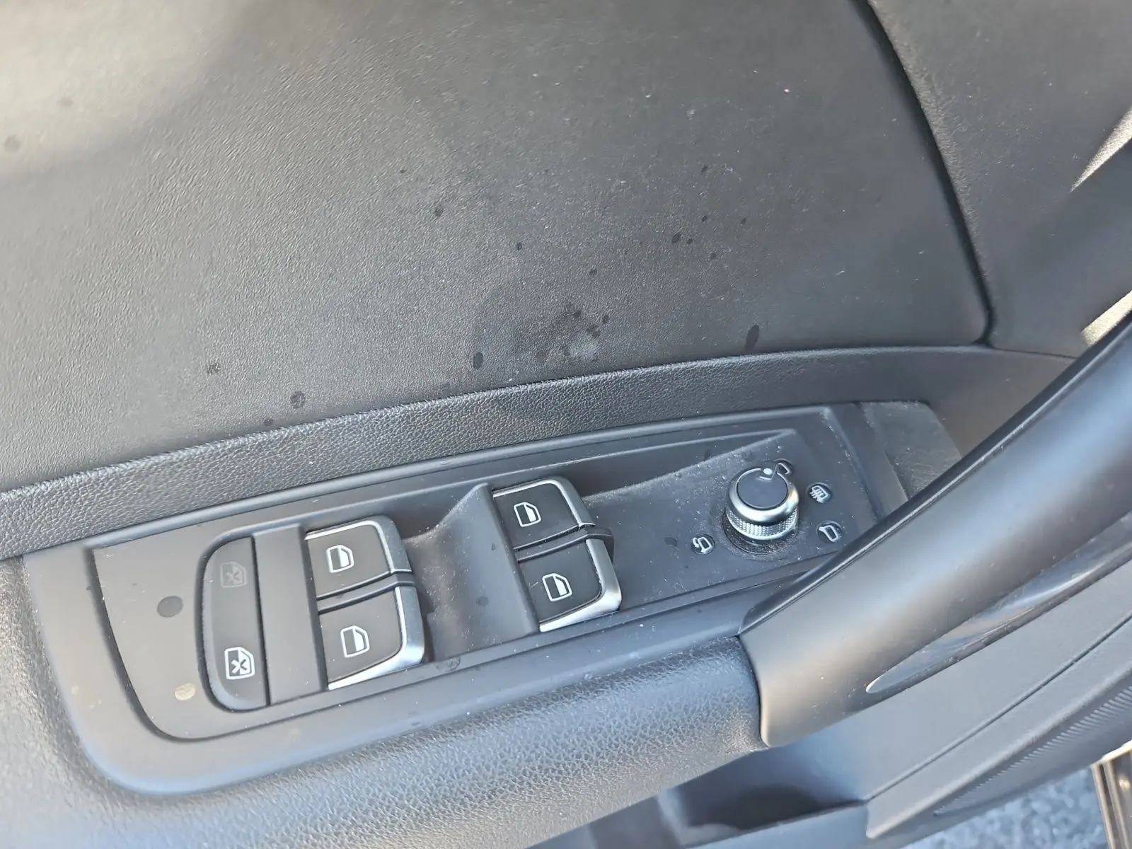Gros plan sur les commandes des vitres et des rétroviseurs côté conducteur de l’Audi A1 Sportback noire de 2016.