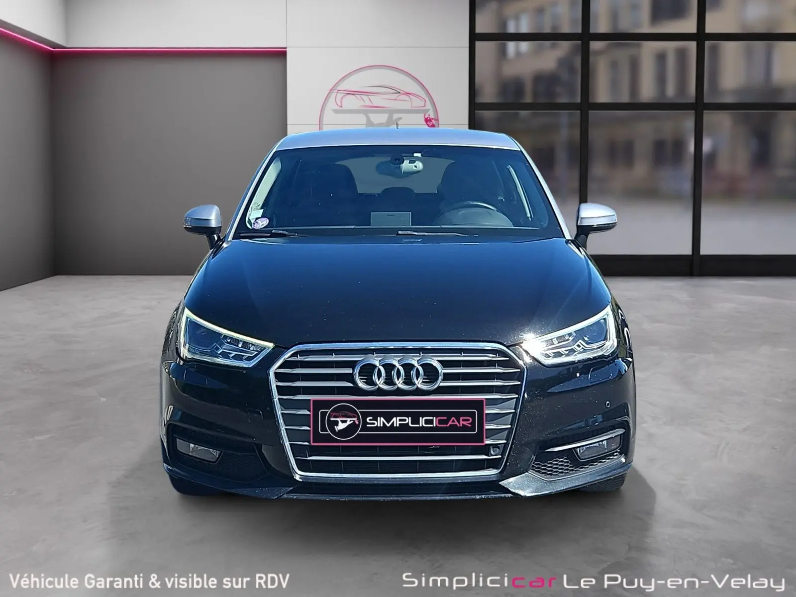 Vue avant d'une Audi A1 Sportback noire de 2016 avec calandre chromée et phares LED allumés.