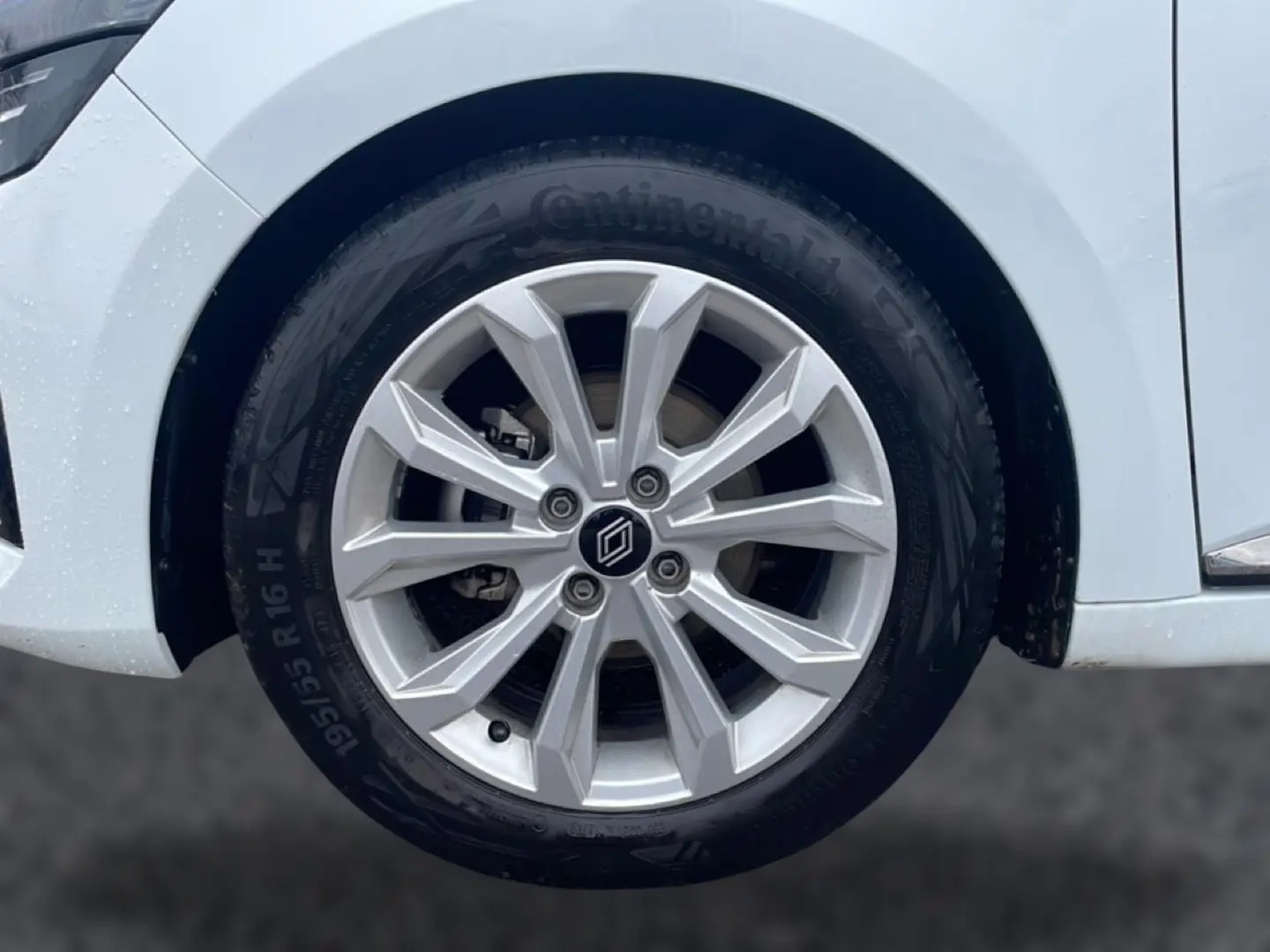 Gros plan sur la roue avant droite de la Renault Clio V blanche, avec jante alliage 16 pouces et logo central.