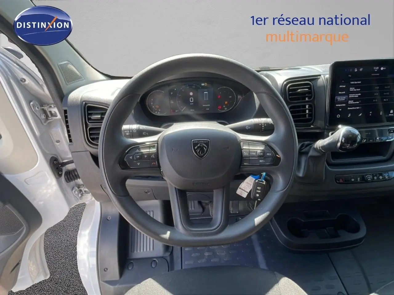 Vue intérieure centrée sur le volant Peugeot d'un Boxer Fourgon blanc banquise avec tableau de bord numérique et écran tactile.