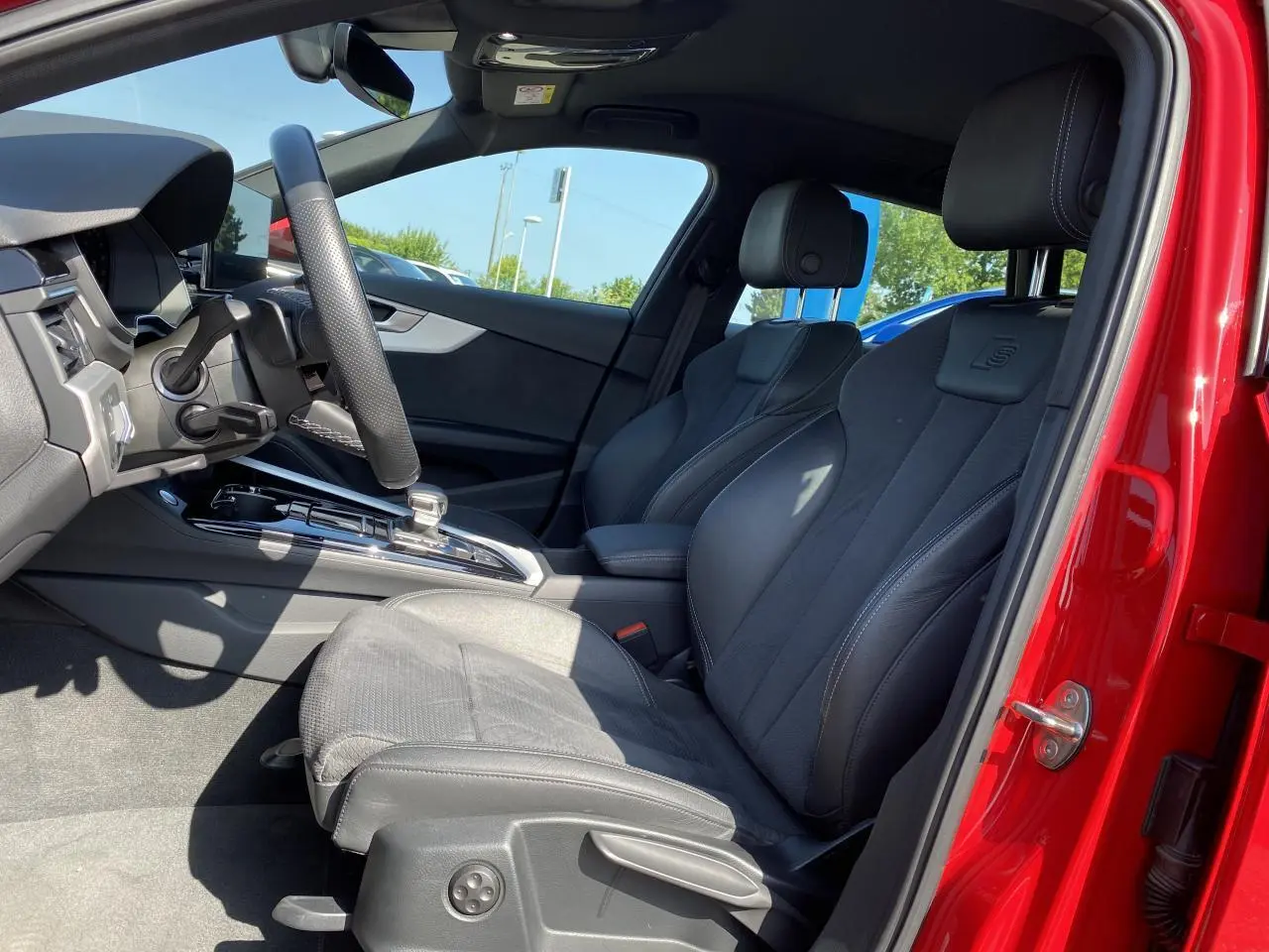 Vue intérieure côté conducteur de l'Audi A4 Avant S line rouge tango, sièges sport en cuir avec logo S embossé.