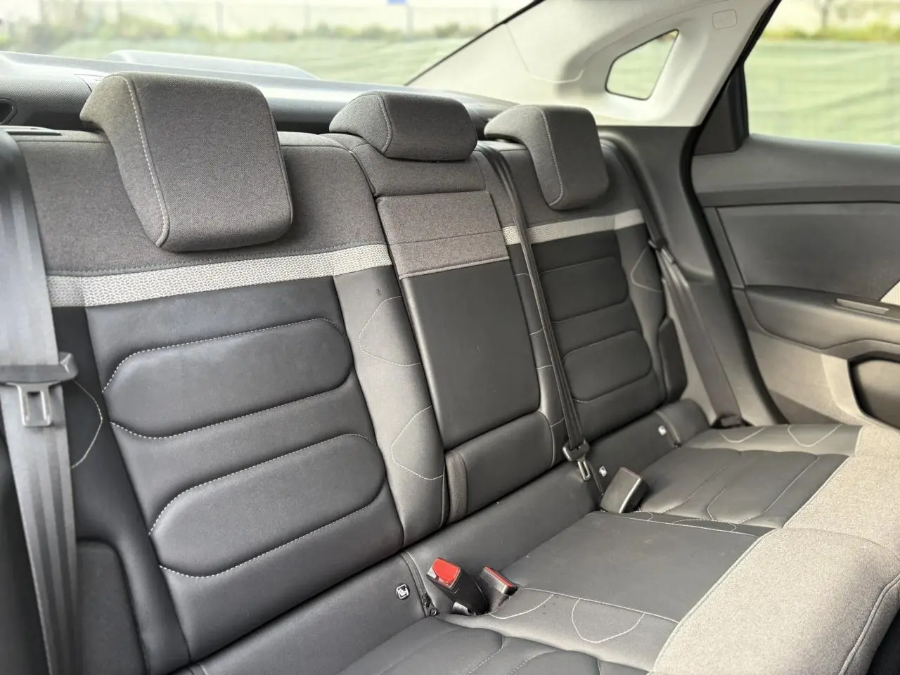 Vue intérieure des sièges arrière en tissu gris chiné et toile noire du Citroën C4 X 2024, avec ceintures et appuie-têtes.