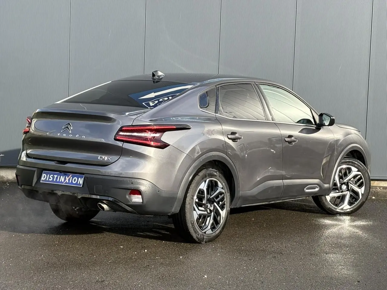 Vue 3/4 arrière droite d'une Citroën C4 X gris Platinium avec jantes alliage et feux LED distinctifs.