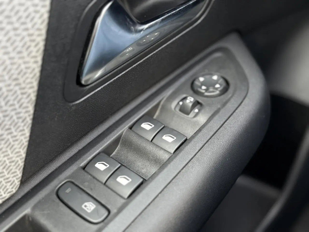 Gros plan sur les commandes de lève-vitres et rétroviseurs côté conducteur d'une Citroën C4 X gris Platinium.