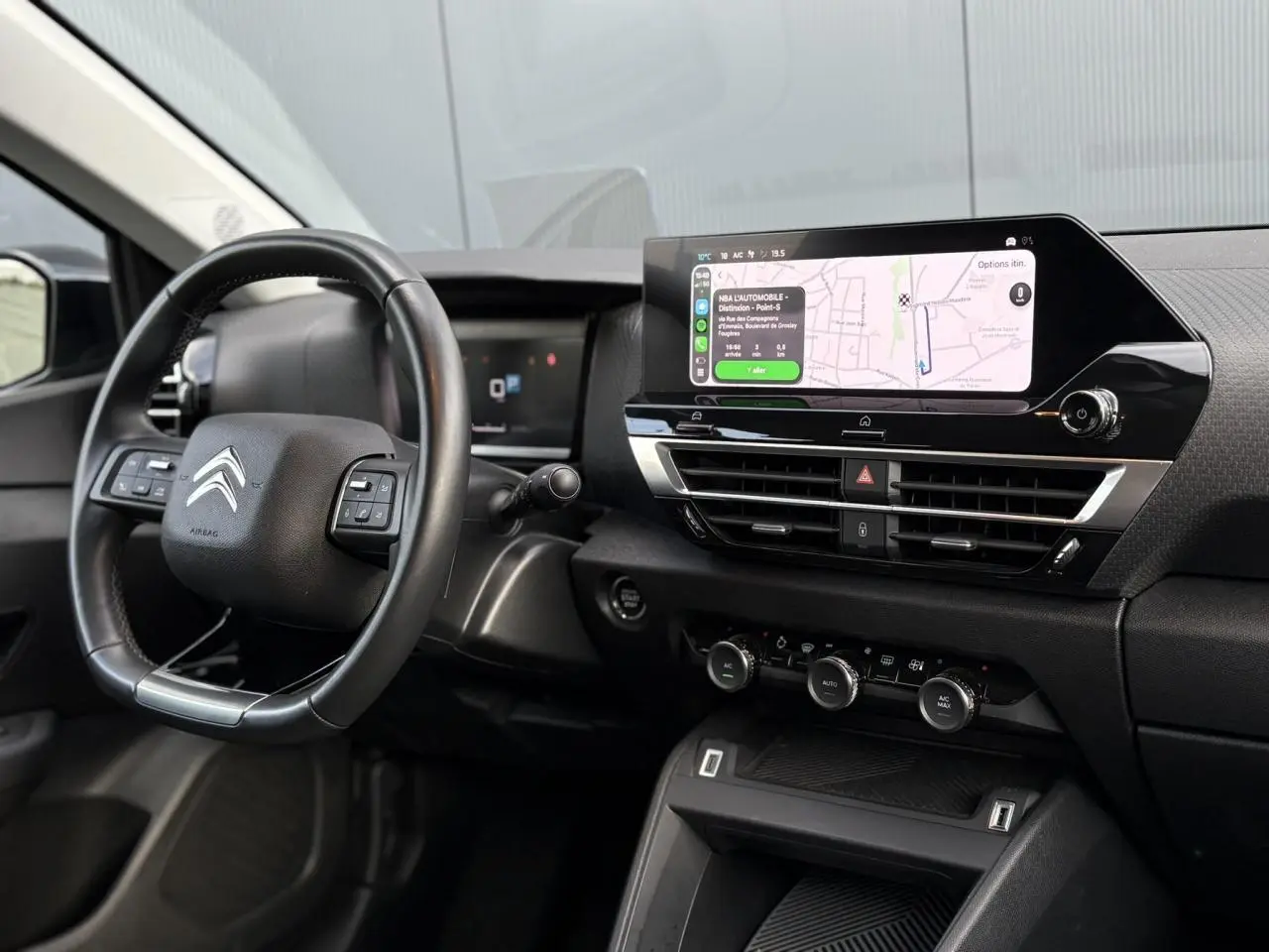 Vue intérieure côté conducteur du tableau de bord noir avec écran tactile 10 pouces affichant la navigation du Citroën C4 X 2024.