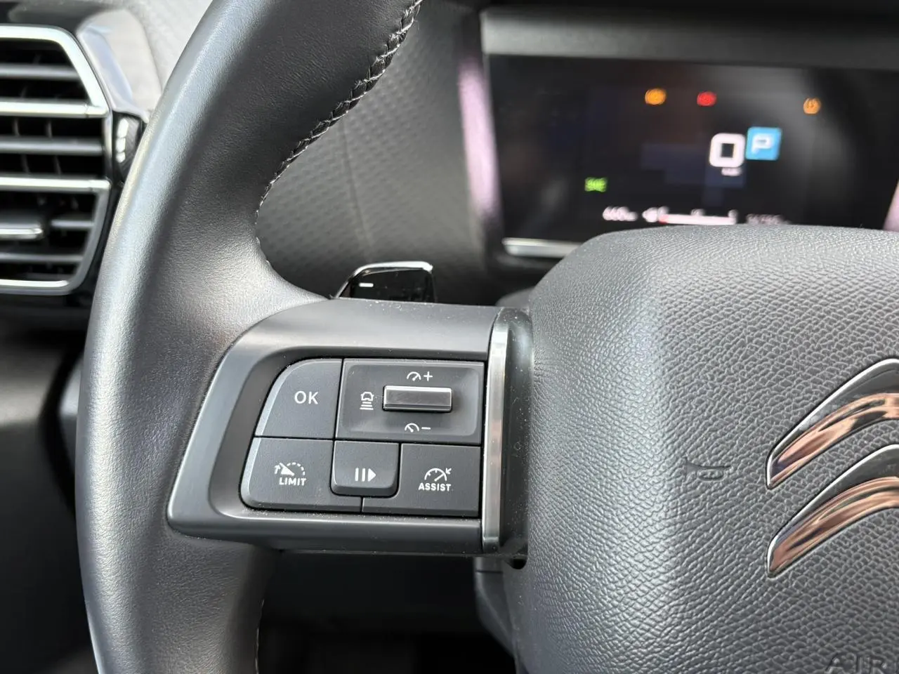Gros plan sur le côté gauche du volant cuir noir de la Citroën C4 X 2024 avec commandes du régulateur adaptatif.