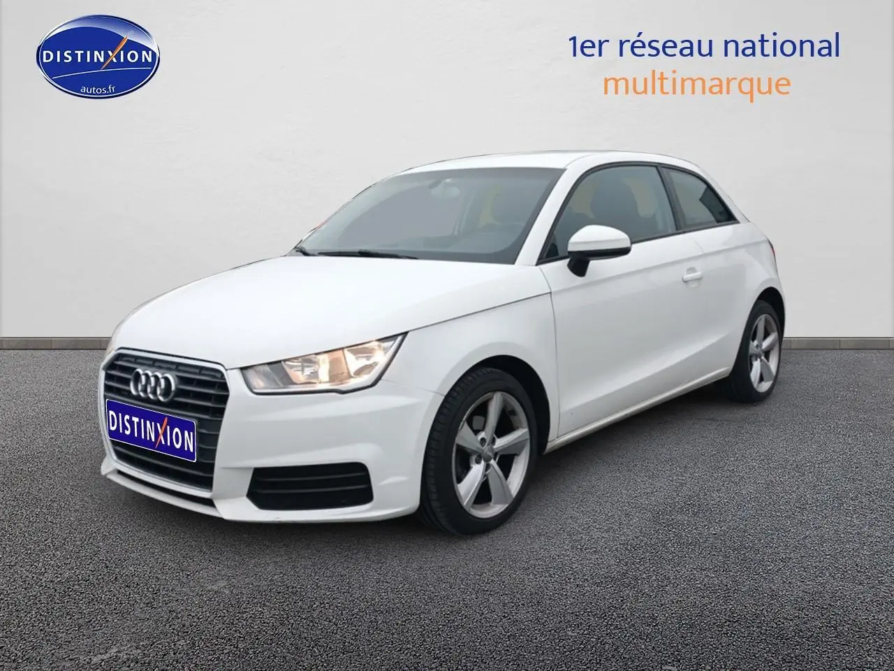 Audi A1 blanc vue 3/4 avant droit avec jantes alu et phares allumés sur fond neutre.