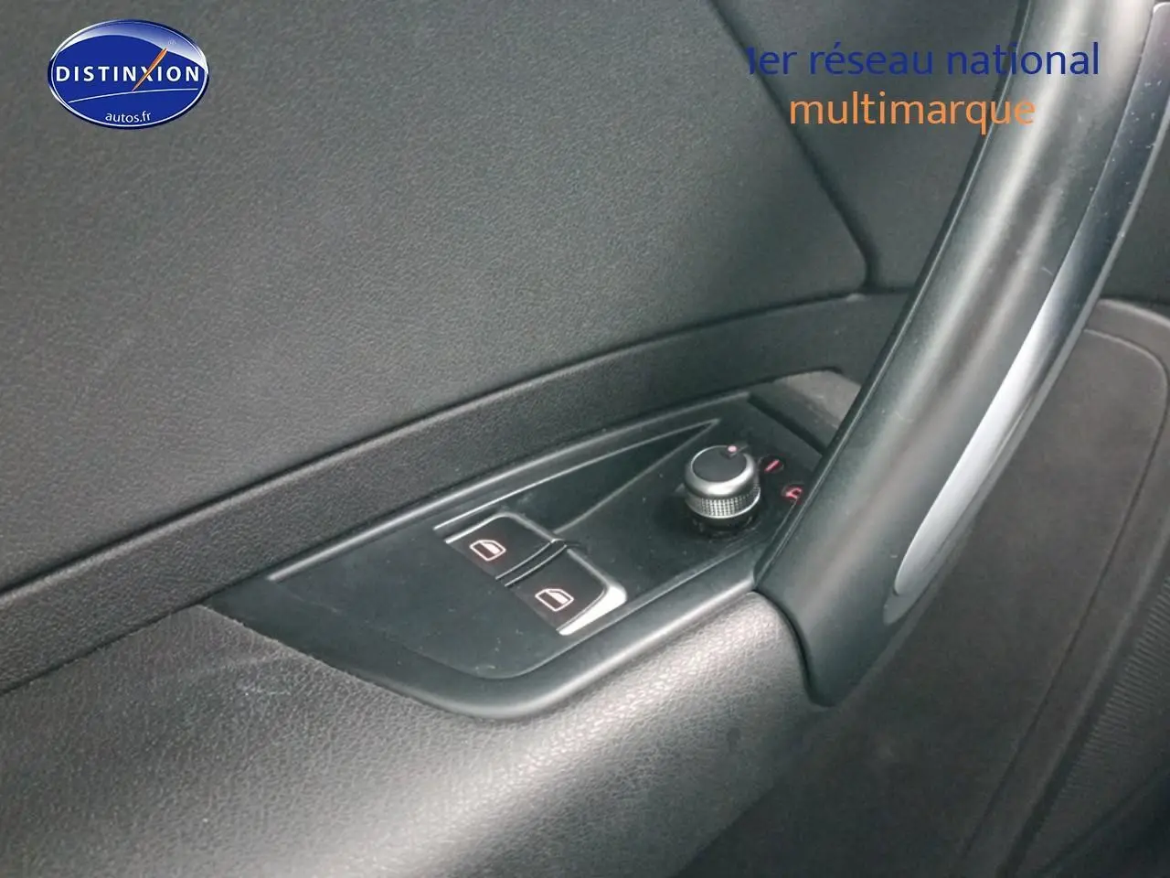 Gros plan sur les commandes des vitres électriques et rétroviseurs sur la porte côté conducteur d'une Audi A1 blanche.