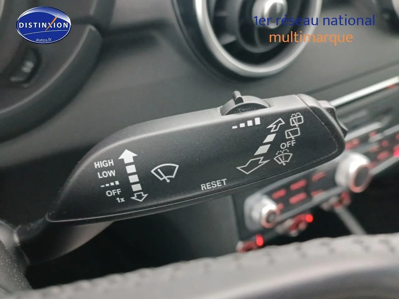 Gros plan sur la commande d’essuie-glace dans l’habitacle d’une Audi A1 blanche, tableau de bord en arrière-plan flou.