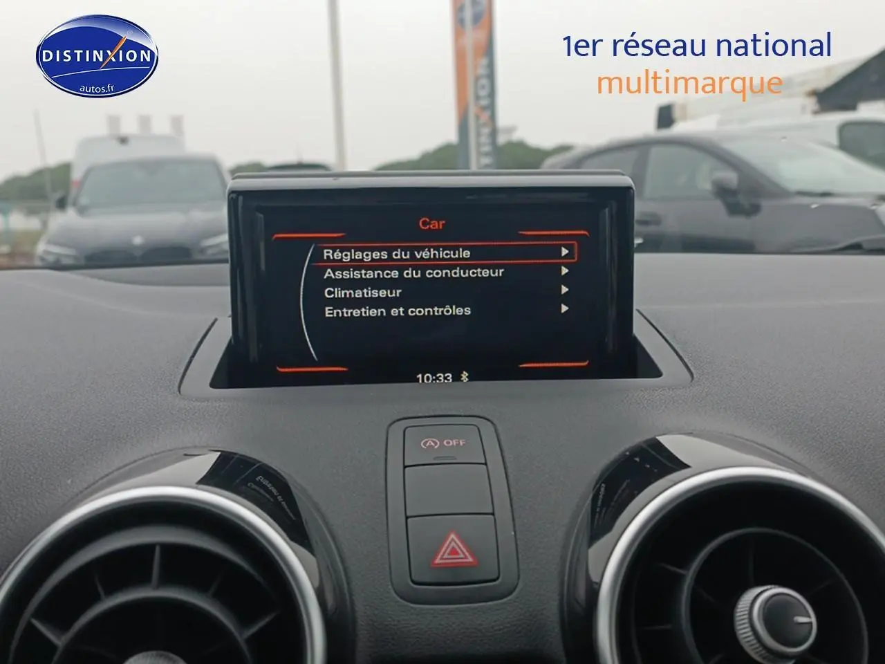 Écran multifonction au centre du tableau de bord d'une Audi A1 blanche, vue intérieure frontale rapprochée.