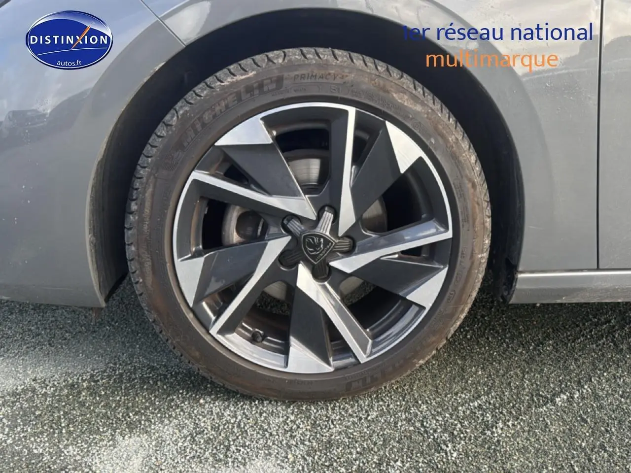 Gros plan sur la roue avant gauche avec jante alu bicolore du Peugeot 308 gris sélénite 2024.