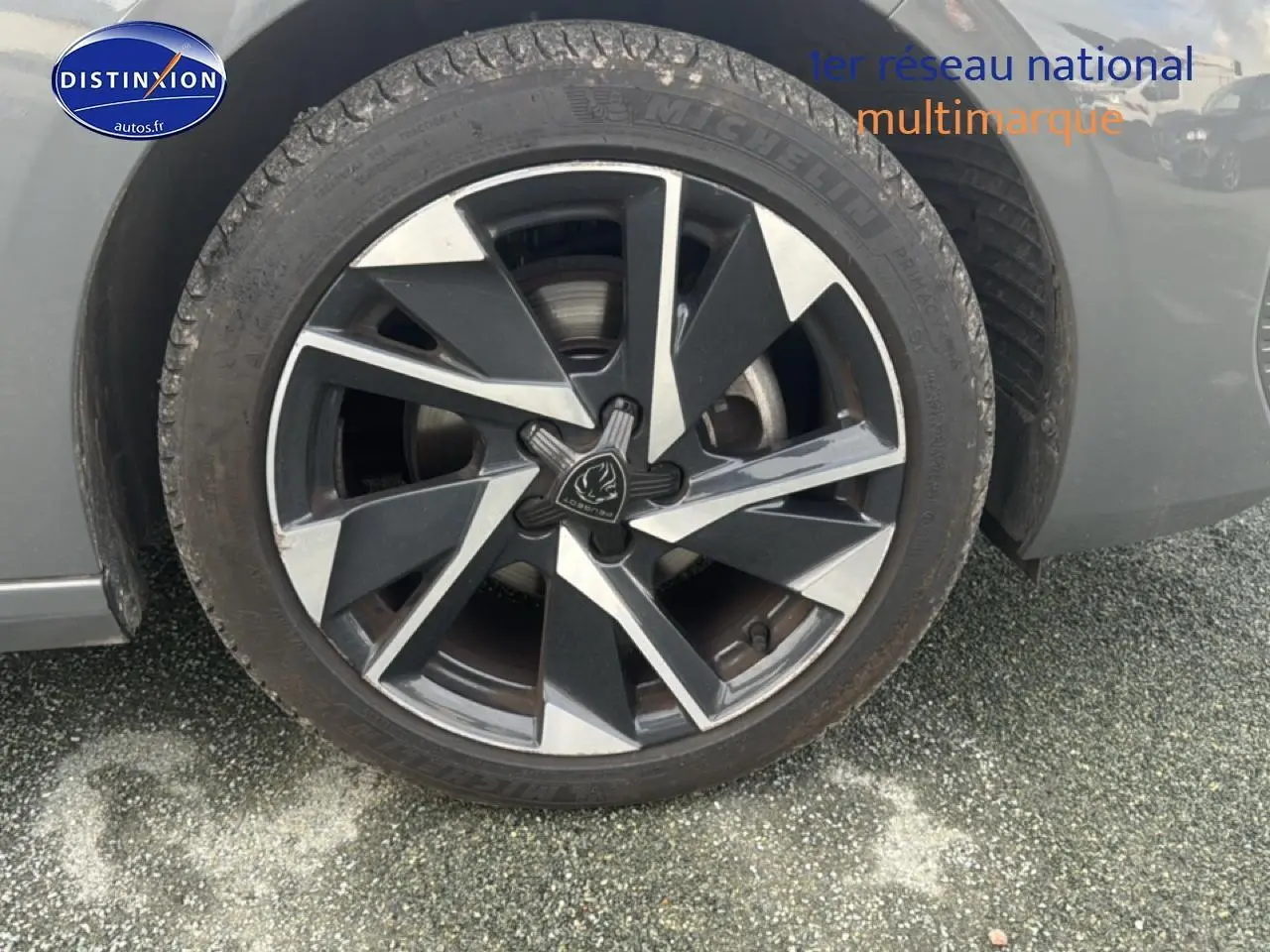 Gros plan sur la roue avant droite avec jante alu bicolore du Peugeot 308 gris sélénite 2024.