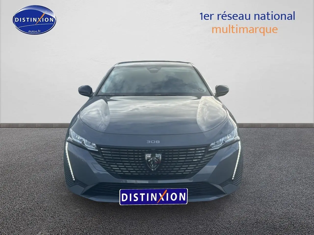 Vue frontale d'une Peugeot 308 gris sélénite 2024 avec calandre noire et feux LED verticaux allumés.