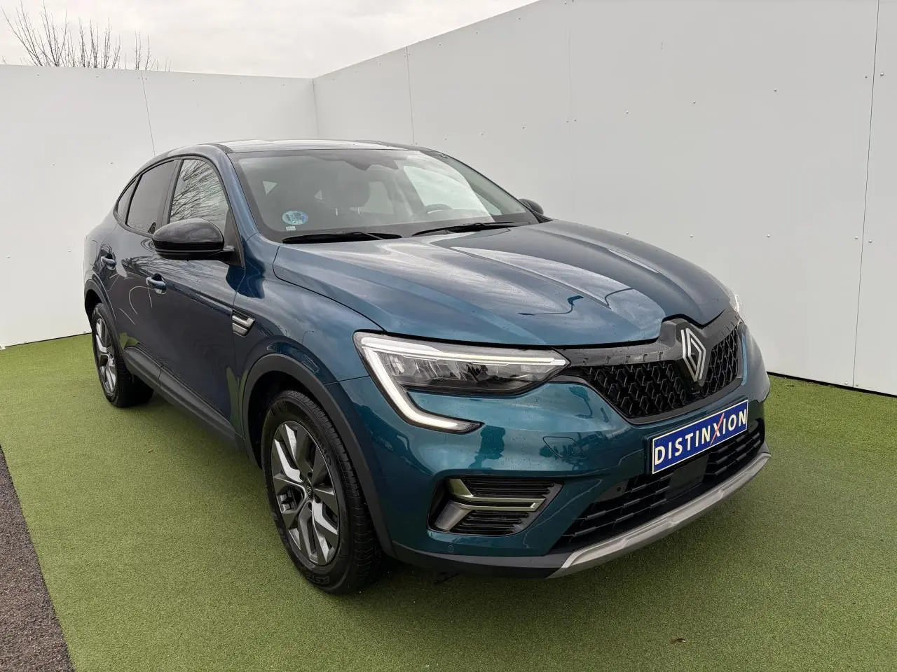 Renault Arkana bleu Zanzibar en 3/4 avant, avec calandre noire et jantes alliage grises visibles.