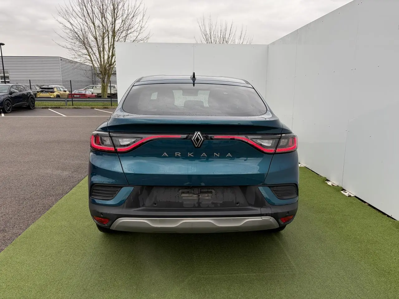 Vue arrière d'une Renault Arkana 2025 en bleu Zanzibar métallisé avec feux LED reliés par un bandeau lumineux rouge.