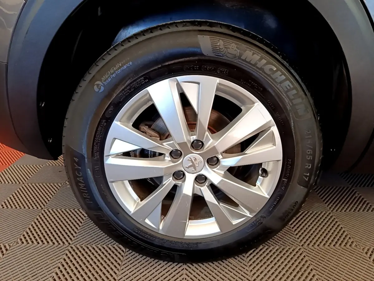 Gros plan sur la roue avant droite du Peugeot 5008 gris clair, avec jante alliage et pneu Michelin.
